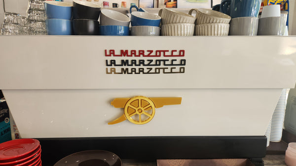 La Marzocco coffee machine with stacked plates and cups in a cafe setting